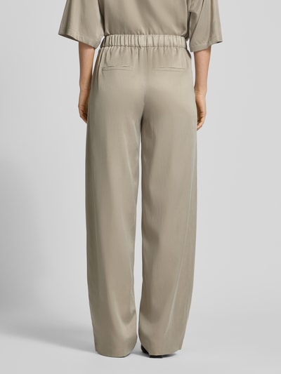 Frauenmodel trägt Wide Fit Stoffhose mit elastischem Bund Modell 'Consider' von Drykorn in Beige mit Gesäßtaschen, Ganzkörperansicht Rückansicht. Cupro-Mix mit Baumwoll-Anteil, glatte Textur.