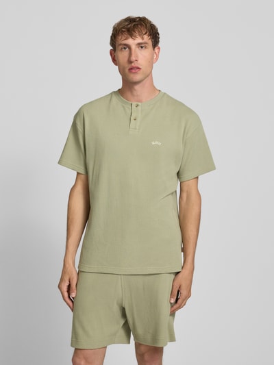 Männermodel trägt Henley-Shirt mit Strukturmuster und Label-Stitching von BLKVIS in hellem Grün, Reine Baumwolle, Regular-Fit, Rundhalsausschnitt, Knopfleiste, Rückenlänge 72 cm bei Größe M, Ganzkörperansicht von vorne.