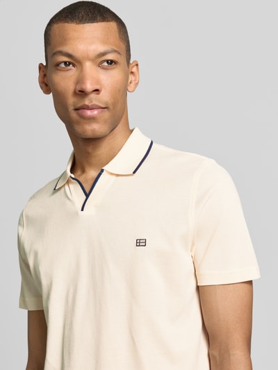 Männermodel trägt Modern Fit Poloshirt mit Logo-Stitching von Christian Berg Men in Creme, feine Baumwollstruktur, Nahaufnahme Oberkörper.