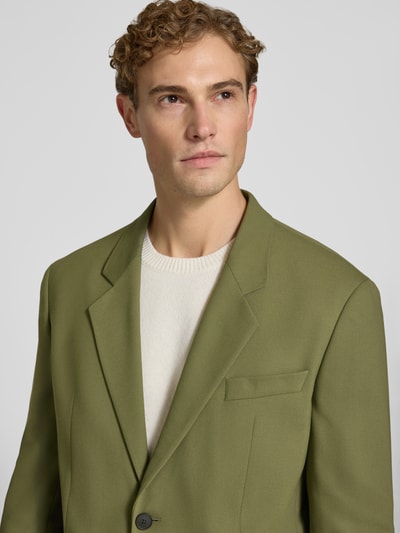 Männermodel trägt Regular Fit Sakko mit Viskose-Anteil Modell 'Karlo243X' von HUGO in Olivgrün, glatte Oberfläche, Nahaufnahme Oberkörper.
