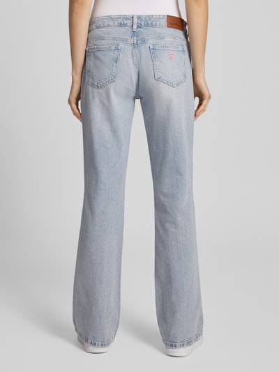 Frauenmodel trägt Bootcut Jeans im Used-Look von Guess Jeans in hellblauem Baumwoll-Elasthan-Mix mit Label-Detail, Ganzkörperansicht Rückansicht.