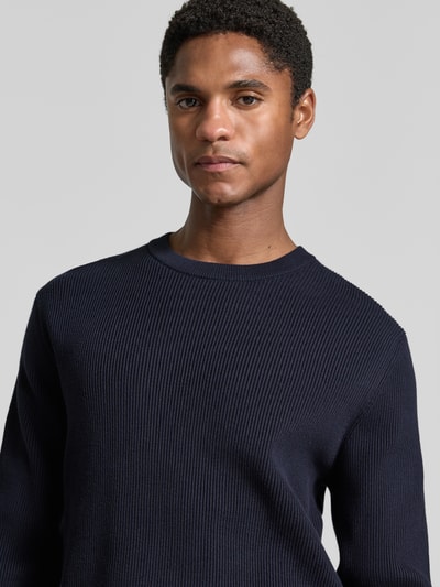 Männermodel trägt Slim Fit Strickpullover Baumwoll-Mix von Lindbergh, gerippte Optik, Rundhalsausschnitt, Nahaufnahme Oberkörper.