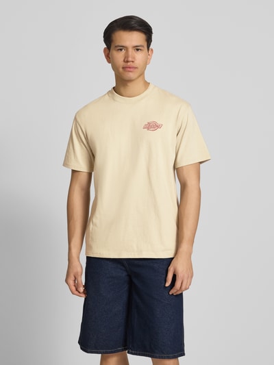 Männermodel trägt Herren T-Shirt mit Logo Modell 'MILLVILLE' von Dickies in Beige aus Reine Baumwolle, Relaxed-Fit, Rundhalsausschnitt, Ganzkörperansicht von vorne. Rückenlänge bei Größe M: 70 cm.