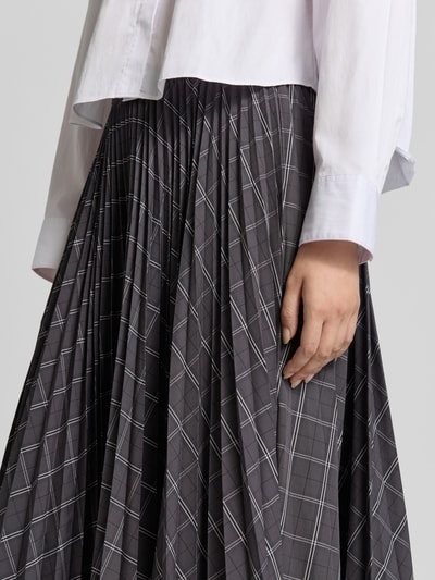 Frauenmodel trägt Midirock mit elastischem Bund Modell 'AURORA' von Cph Muse im Allover-Look mit Falten, Nahaufnahme Oberkörper. Material-Mix mit Viskose-Anteil, grafisches Muster in Grau und Weiß, A-Linie.