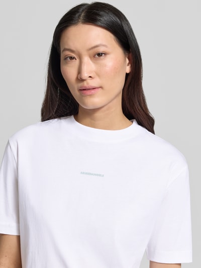 Frauenmodel trägt Damen T-Shirt von Armedangels, Modell 'TARJAA', Optik: Unifarben, Regular-Fit, Logo-Stitching, Motiv-Print, Rundhals, Kurzarm, Materialverarbeitung: Jersey, Reine Baumwolle, Nahaufnahme Oberkörper.
