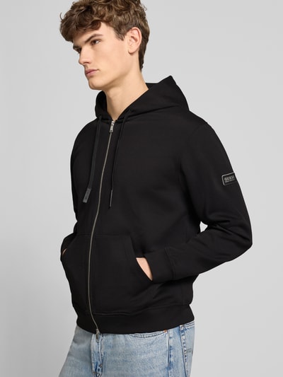 Mannenmodel draagt zwarte Sweatjacke mit Reißverschluss van Guess, katoenmix met capuchon, losse fit, steekzakken, rits, vooraanzicht bovenlichaam
