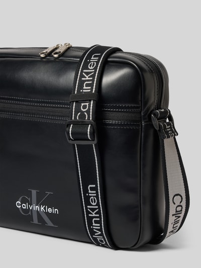 Produktfoto, Laptoptasche mit Label-Schriftzug Modell 'BOLD LOGO WEBBING LAPTOP' von CK Calvin Klein für Herren, schwarze glatte Oberfläche, weiße Kontrast-Schriftzüge, rechteckige Form, sichtbare Textur des robusten Materials.