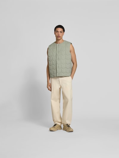 Männermodel trägt Regular Fit Weste in Stepp-Optik von MAISON KITSUNÉ, Rundhalsausschnitt, Knopfleiste, Eingrifftaschen, Ganzkörperansicht von vorne.