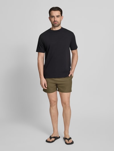 Männermodel trägt Relaxed Fit Badeshorts mit Logo-Stitching von Emporio Armani in Olivgrün, elastischer Bund mit Tunnelzug, Ganzkörperansicht von vorne.