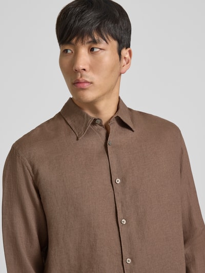 Männermodel trägt Regular Fit Leinenhemd aus reinen Leinen Modell 'Lawrence' von Jack & Jones Premium, braun, Kentkragen, Langärmelig, durchgängige Knopfleiste, Nahaufnahme Oberkörper. Rückenlänge bei Größe M: 74 cm, Schulterbreite 45 cm, Ärmellänge 66 cm.
