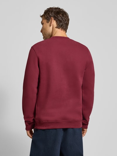 Männermodel trägt Regular Fit Sweatshirt aus reiner Baumwolle Modell 'BAARO' von ARMEDANGELS in Dunkelrot, glatte Struktur, Ganzkörperansicht Rückansicht. Herren Sweatshirt von ARMEDANGELS.