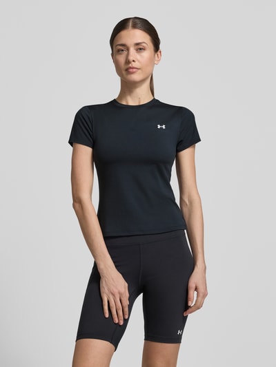 Vrouwenmodel draagt T-shirt met ronde hals en logoprint van Under Armour, zwart, materiaalmix met stretch, slim fit, ruglengte maat S 49 cm, volledige lichaamsaanzicht van voren.