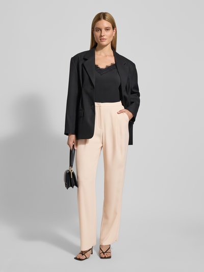 Frauenmodel trägt Stoffhose mit Bundfalten von Emporio Armani in Beige, lockerer Schnitt, französische Eingrifftaschen, Ganzkörperansicht von vorne.