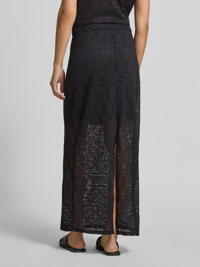 Frauenmodel trägt Leicht ausgestellter Midi-Rock aus Spitze mit elastischem Bund Modell 'MAYA' von Vero Moda in Schwarz, unifarben, transparenter Spitzenrock mit blickdichtem Unterrock, Gehschlitz am Saum, Ganzkörperansicht Rückansicht.