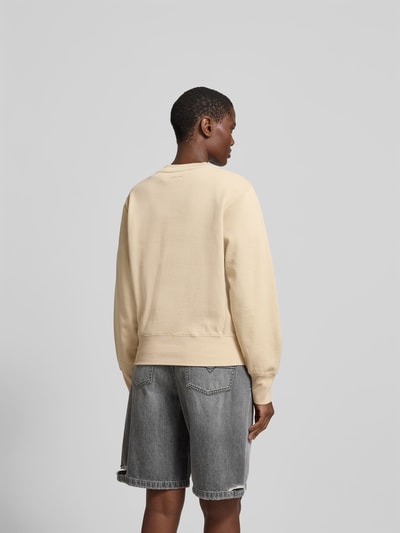 Frauenmodel trägt Sweatshirt aus reiner Baumwolle von Anine Bing in Beige mit Label-Detail, lockere Passform, elastische Abschlüsse, Rückenlänge bei Größe S 56 cm, Ganzkörperansicht Rückansicht.