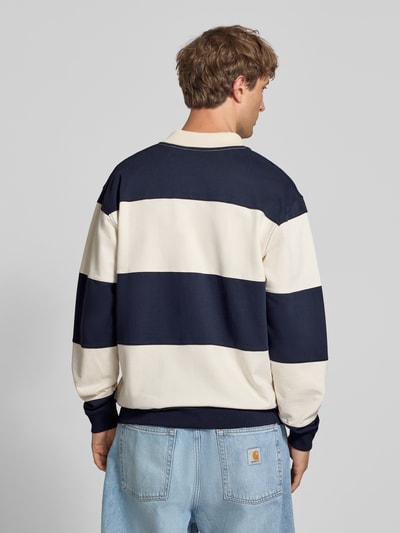 Männermodel trägt Relaxed Fit Troyer aus reiner Baumwolle von Marc O'Polo DENIM in Dunkelblau und Beige, Ganzkörperansicht Rückansicht.
