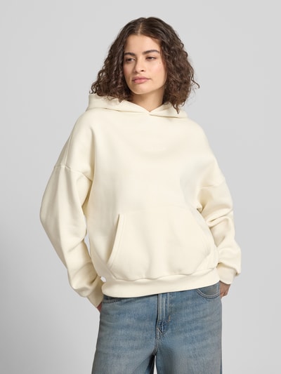 Frauenmodel trägt Relaxed Fit Sweatshirt mit Logo-Print von Review in Creme aus Baumwoll-Mix, mit Logo-Stitching, Känguru-Tasche und elastischen Abschlüssen, Ganzkörperansicht von vorne.
