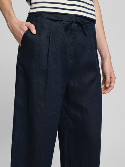 Frauenmodel trägt Leinenhose mit Bindegürtel von Christian Berg Woman in Dunkelblau, Reines Leinen, Knopfverschluss, Nahaufnahme Oberkörper.