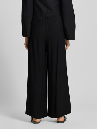 Frauenmodel trägt schwarze Wide Fit Stoffhose aus Viskose-Mix Modell 'Frencis' von STEHMANN, elastischer Bund, Ganzkörperansicht Rückansicht.