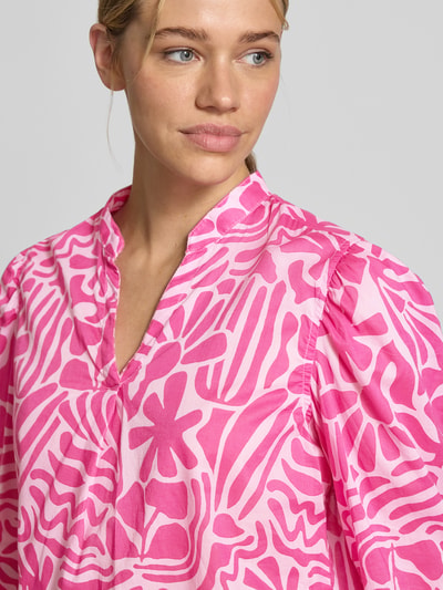 Vrouwenmodel draagt Relaxed Fit Tunika-Bluse mit floralem Allover-Print van Christian Berg Woman in roze en wit katoen, tunica-hals, driekwartmouw, elastische mouwuiteinden, detailopname bovenlichaam.