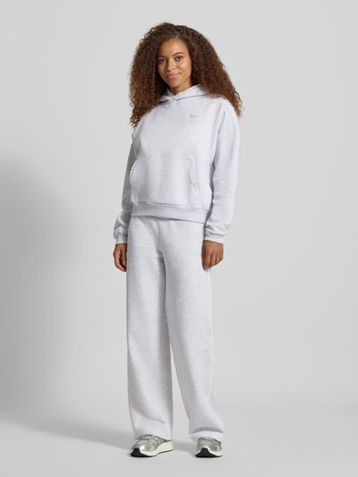 Frauenmodel trägt Relaxed Fit Hoodie mit Baumwoll-Anteil von REVIEW, hellgrau, Känguru-Tasche, Spitzenbesatz, Logo-Stitching, Ganzkörperansicht von vorne.