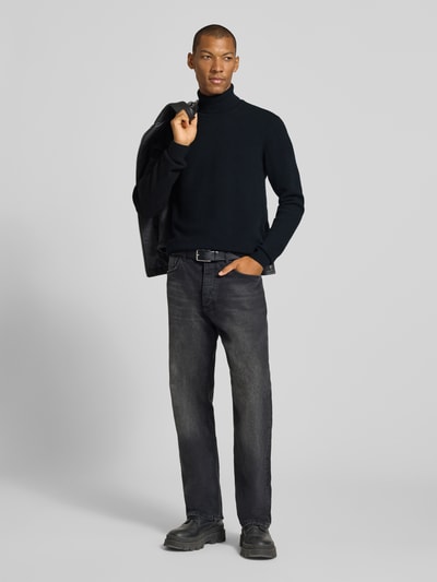 Männermodel trägt Slim Fit Rollkragenpullover aus Woll-Mix Modell 'Karl' von Casual Friday in Schwarz, gerippte Abschlüsse, Ganzkörperansicht von vorne.