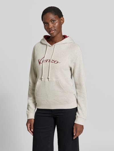 Frauenmodel trägt Hoodie aus reiner Baumwolle von KENZO in Beige mit Label-Print, kontrastiver Kapuze, Känguru-Tasche, taillierte Passform, Ganzkörperansicht von vorne.