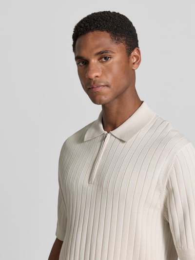 Männermodel trägt Regular Fit Poloshirt mit kurzem Reißverschluss von Drykorn aus Reine Baumwolle, Nahaufnahme Oberkörper. Modell 'NIIVAN', Rückenlänge 68 cm bei Größe M, Farbe Beige, feine Rippstruktur.