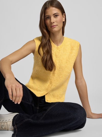 Modelka kobieca nosi Regular Fit Strickjacke aus Woll-Mix od Selected Femme, żółty kolor, melanżowa faktura, bez rękawów, widok na cały tułów z przodu.