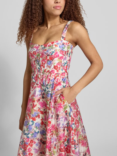 Frauenmodel trägt Cocktailkleid im Allover-Look Modell 'LILAH' von Bardot, bunte Blumenfarben, taillierter Schnitt, Nahaufnahme Oberkörper.