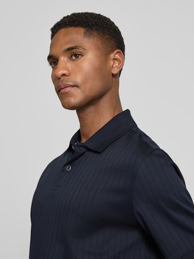 Männermodel trägt Regular Fit Poloshirt mit Knopfleiste von bugatti aus reiner Baumwolle, Strukturmuster, navyblau, Nahaufnahme Oberkörper.