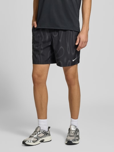 Männermodel trägt Regular Fit Sportshorts mit Dri-FIT-Technologie von Nike, schwarz mit weißem Logo, Herren Sportshorts, Ganzkörperansicht von vorne.