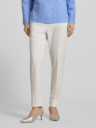 Frauenmodel trägt Hose aus Viskose-Mix mit Bügelfalten von Comma in Creme, Slim-Fit, glatte Textur, Eingrifftaschen, Ganzkörperansicht von vorne. Bundweite bei Größe 36: 36 cm, Innenbeinlänge bei Größe 36: 72 cm, Stretch-Anteil.