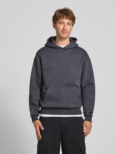 Männermodel trägt Relaxed Fit Sweatshirt aus katoenmix met capuchon, labeldetail en kangoeroezak van REVIEW, kleur donkergrijs, herensweatshirt, ruglengte bij maat M 68 cm, mouwlengte bij maat M 62 cm, elastische boorden, ganzkörperansicht van voren.