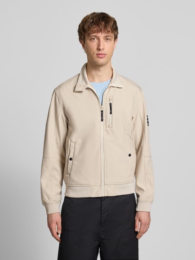 Männermodel trägt Regular Fit Bomberjacke mit Stehkragen Modell 'Parker' von Jack & Jones in Beige, Softshell, Vorderansicht, Ganzkörperansicht von vorne. Zu sehen sind Napoleontasche, Druckknopf-Eingrifftaschen, elastische Abschlüsse, Maße M: Rückenlänge 67 cm, Schulterbreite 43 cm, Brustweite 55 cm, Ärmellänge 65 cm.
