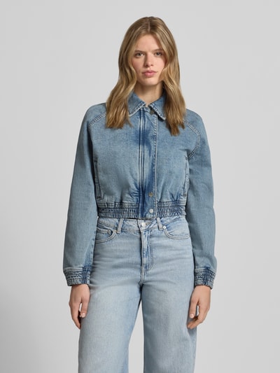 Frauenmodel trägt Relaxed Fit Jeans-Bomberjacke aus Baumwoll-Mix von Hugo Blue in Denim-Optik mit Umlegekragen und verdecktem Reißverschluss, Ganzkörperansicht von vorne.