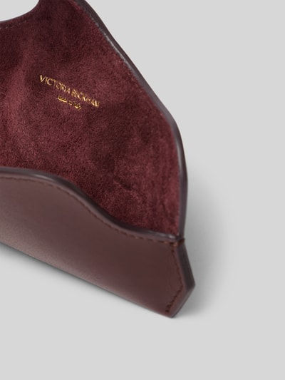 Productfoto, Sonnenbrillenetui aus Leder van Victoria Beckham in bruin met label-detail, suède textuur, gevoerd hoofdvak, draaghengsel, overslag.
