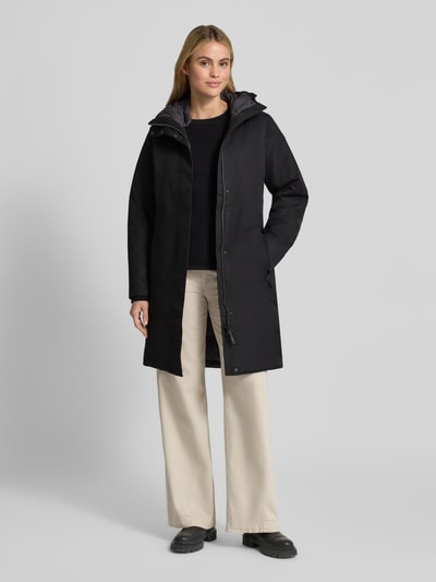 Modelka nosi czarny Parka mit Kapuze und Eingrifftaschen Modell 'GW66' von G.I.G.A. DX, krój regular fit, widok na całą sylwetkę z przodu. Długość tyłu w rozmiarze 36: 94 cm, szerokość ramion w rozmiarze 36: 42 cm, szerokość klatki piersiowej w rozmiarze 36: 47 cm, długość rękawa w rozmiarze 36: 65 cm.