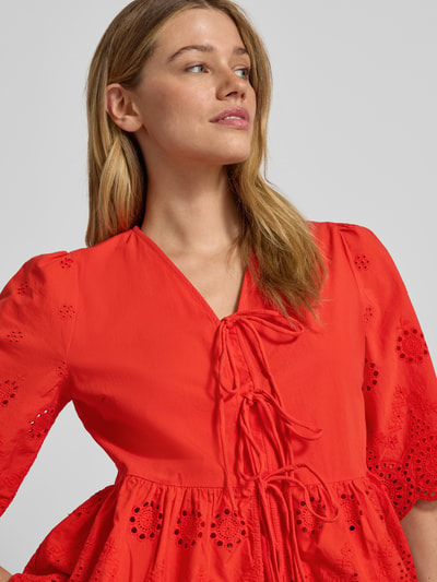 Kobiece model nosi bluzkę Regular Fit Bluse mit Lochstickereien Modell 'Cornelia' od YAS, haft angielski, krój regular fit, dekolt w serek, rękaw o dł. 1/2, ozdobna kokarda, długość tyłu w rozmiarze 36: 56 cm, długość rękawów w rozmiarze 36: 37 cm, intensywny czerwony kolor, gładka i ażurowa faktura, detaliczna faktura haftu, nahaufnahme górnej części ciała.