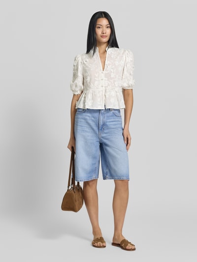 Frauenmodel trägt Regular Fit Bluse mit V-Ausschnitt Modell 'CAPUCHIN' von MANGO aus weißer Baumwolle mit Stitchings, Knopfleiste und 3/4-Arm, Ganzkörperansicht von vorne.