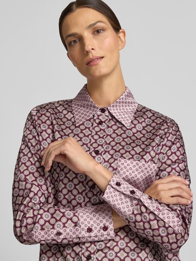 Frauenmodel trägt Relaxed Fit Hemdbluse Modell 'CAMICIA' von Liu Jo White aus Satin mit geometrischem Muster, Nahaufnahme Oberkörper. Damen Hemdbluse von Liu Jo White, Satin, Relaxed Fit, Hemdblusenkragen, langärmelig, Brusttasche, Rückenlänge bei Größe 36: 64 cm, Ärmellänge bei Größe 36: 62 cm.