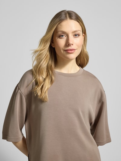 Modelka kobieca ma na sobie Damski t-shirt 'T-Shirt aus Modal-Mix mit Rundhalsausschnitt' od Jake*s Casual, mieszanka modalu z dodatkiem streczu, krój relaxed fit, okrągły dekolt, odcień beżowy, gładka tekstura, widok na górną część ciała z przodu.