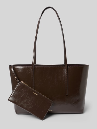 Produktfoto, brązowa Henkeltasche mit Label-Detail von CK Calvin Klein o błyszczącej teksturze, kontekst: damska torebka od CK Calvin Klein