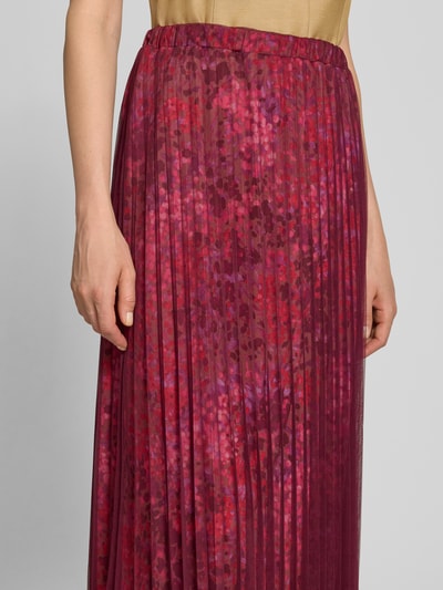 Frauenmodel trägt Midirock mit Plisseefalten im Allover-Look von Rich & Royal, Mesh, A-Linie, rote Töne, Nahaufnahme Oberkörper.