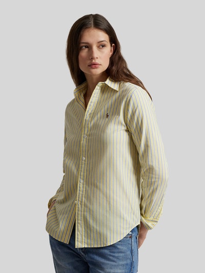 Frauenmodel trägt Regular Fit Hemdbluse aus reiner Baumwolle von Polo Ralph Lauren mit gelb-blauem Streifenmuster, Logo-Stitching, Oxford-Gewebe, Hemdkragen und Knopfleiste; Ganzkörperansicht von vorne.