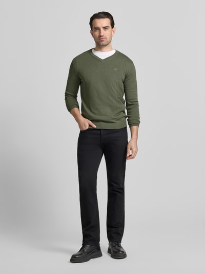 Männermodel trägt Regular Fit Pullover aus reiner Baumwolle von Tom Tailor in Olivgrün, Feinstrick, unifarben, Logo-Stitching, Ganzkörperansicht von vorne.