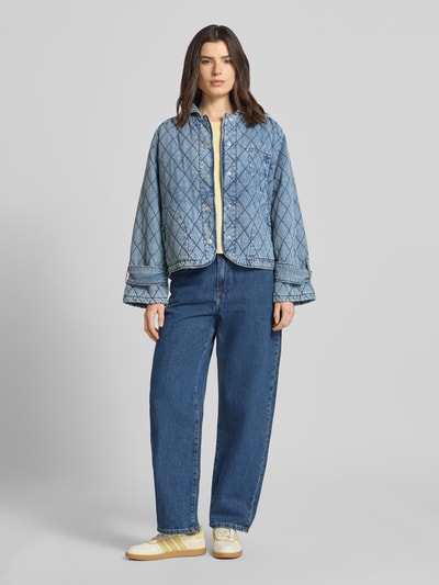Frauenmodel trägt Jacke mit Steppnähten Modell 'Viola' von LOLLYS LAUNDRY aus Baumwoll-Mix in Denim-Optik, Relaxed-Fit, Umlegekragen, Knopfleiste, Eingrifftaschen, mittleres Blau, strukturierte Oberfläche, Ganzkörperansicht von vorne.