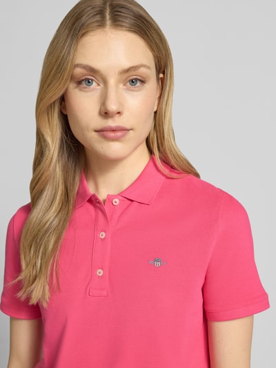 Frauenmodel trägt Poloshirt mit Logo-Stitching und Polokragen von Gant in Pink, Reine Baumwolle, Regular-Fit, Kurze Knopfleiste, Nahaufnahme Oberkörper.