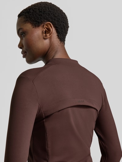 Frauenmodel trägt Jacke mit Zweiwege-Reißverschluss Modell 'Sense' von aim'n, Material-Mix in Braun, Detailaufnahme Rückenansicht. Damen Jacke mit Stehkragen und Stretch-Anteil, Slim Fit, Rückenlänge 53 cm.