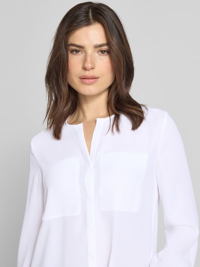 Frauenmodel trägt Regular Fit Bluse mit Brusttaschen von Marc Cain, Tunika-Ausschnitt, weiße Farbe, langärmelig, Nahaufnahme Oberkörper.